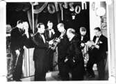 Jonssons orkester, åtta män med musikinstrument.
Text på bilden: 