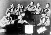 Orkester, åtta män med musikinstrument.