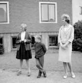 En kvinna och två barn.Bostadshus i bakgrunden.