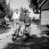 Två pojkar med en cykel.