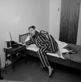 Sovrumsinteriör, en man i pyjamas vid telefonen, 