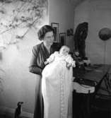 Rumsinteriör, en kvinna och en baby, barndop.
Fru Falk