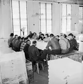 Verkstadsinteriör, grupp vid bordet, avskedsfest för Kalle Wärnberg.