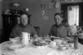 Rumsinteriör, två unga män i militäruniform vid bordet.
Till höger Martin Pettersson (givarens farbror).