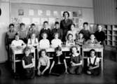 Vasaskolan, klassrumsinteriör, 20 skolbarn med lärarinna fru Britta Sandahl.
Klass 2s, sal 15 eller 16 (kortet togs i sal 16).