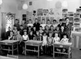 Klassrumsinteriör, 27 skolbarn med lärarinna.