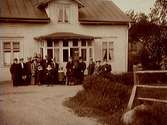 Bostadshus, barn och vuxna framför huset.
Bilden tagen troligen 1906.