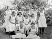 En grupp skolköksflickor fotograferade utomhus. Flickorna har ljusa förkläden och huvuddukar.