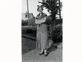 Kvinnoporträtt. Maj Winqvist? (Dotter till Johan och Amelie Winqvist) fotograferad utomhus. I bakgrunden korsningen Fastarpsvägen - Prästgårdsvägen. Huset fastigheten Älvdalen.