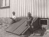 Två pojkar, t v Karl Ivar Rosenqvist och t h Inge Svensson, Lövagård, (uppgiftslämnaren) fotograferade vid en källar-nedgång till ett hus. Fastarpsvägen, Tvååker. 1933 ca.