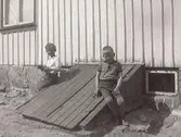 Två pojkar, t v Karl Ivar Rosenqvist och t h Inge Svensson, Lövagård, (uppgiftslämnaren) fotograferade vid en källar-nedgång till ett hus. Fastarpsvägen, Tvååker. 1933 ca.