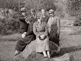 Gruppbild med fyra kvinnor och två män fotograferade vid en sten i en hage.