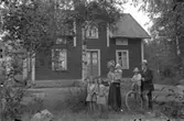 Bostadshus, familjegrupp sex personer framför huset.
Se även bild 2008:35:69.