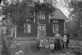 Bostadshus, familjegrupp sex personer framför huset.
Se även bild 2008:35:68.