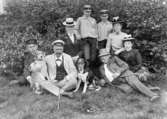 Familjegrupp åtta personer och två hundar i gröngräset.
Sommaren 1901.