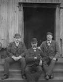 Tre män på trappan till en byggnad.