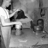 Hattillverkning. Bild 1. 188/67. Sedan stumpen legat i fuktrummet cirka ett dygn är den färdig för formning. Stumpen lägges några sekunder i varm ångkupa, placeras här på bilden på en träkulle som sitter på en underställare och drages. Träformens andra del (för brättet) t.h. på bilden. Bild 2 189/67. Bild av ångkupa av koppar med locket (av textil) uppfällt.