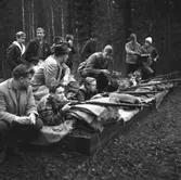 Samrealelever vid skjutbanan.
Stående i rock och hatt magister L. Ranch.
Miltärklädd, Gunnar Granberg.
Skolfröken som antecknar, Kerstin Rickardsson.