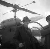 Två män vid en helikopter.
 