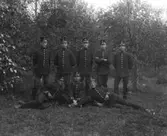 Åtta män, (militärer) fotograferade utomhus.
