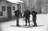 Tre män med skidor står utanför IKHP-stugan i Huskvarna.