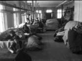 Interiör med kvinnor i arbete på dåvarande Skandinaviska Textilfabriken i Varberg, senare Varbergs yllefabrik och från 1912 Malmö Yllefabriks AB. Här var en av få industrier där kvinnor kunde få jobb och vid år 1900 var de i klar majoritet av de ca 100 anställda vid sekelskiftet 1900. Först tillverkades endast bomullstyger men från 1906 även ylletyger. I lokalen ligger balar med tygsjok. Fabriken låg i kvarteret Vävaren, numera Renen.