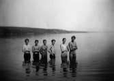 Sex unga män står i vattnet i sjön Lygnern, 1930- 40-tal. Från vänster: okänd, Gösta Gunnarsson, Helmer Garthman samt okända till höger.