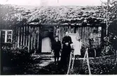 Åsarps sn. Spånggården. Brunabergsslätt, friköpt torp som tillhör Spånggården, Åsarp. Louisa Lood med två barnbarn, föräldralösa, som bodde i stugan. Foto omkring 1915. Louisa Lood var syster till kortets ägare Gunnar Hammars, farfar Anders Johansson. Stugan finns inte bevarad.