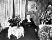 Troligen barnmorksan Carolina Söderlund (1873-1935). På väggen USA:s flagga, kan vara från dottern Ingeborg som emigrerat.