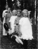 En kvinna och fyra flickor.
Fru Sigrid Thunberg med två döttrar, samt Thea Elfrida och Linnéa Olsson (2:a och 4:de bakifrån).