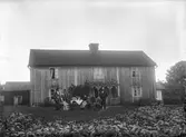 Familj framför hus i Skede, fotografi beställt av disponent Johan Bergfeldt, Vetlanda, cirka 1900.