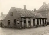 Hus vid Algatan-Brogatan 1890, J P Ekvalls cigarr och tobaksaffär, P Möllers reskoffertar väskor och barnvagnar, L Virgins.