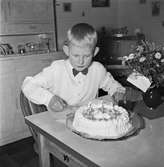 Tom Andersson firar sin nionde födelsedag i sitt hem på Odengatan 22 i Huskvarna. På bordet står en gräddtårta med nio ljus och från sin kamrat Kenneth har han fått blommor med Hjärtliga lyckönskningar på födelsedagen.