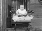 Barnporträtt. Ett barn fotograferat sittande i en gungstol.