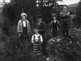 Två kvinnor, en man, en flicka och en pojke fotograferade utomhus, (i en granplantering?) Flickan finns med på bild E6841.