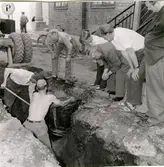 Falköpins Tidnings tomt. Fynd i jorden av en laggad trätunna. 1957. 2. Fynd i jorden av en ornerad kalksten. 1957.