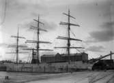Tremastad båt i hamnen, ångkvarnen i bakgrunden, ”vy 1920 A” på asken
	Metallutfällning.