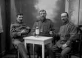 Ateljébild, tre soldater drickandes starka drycker, ”1915 B” på asken
	Metallutfällning, fingeravtryck, repor.