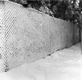 Närbild av staket i skog med snö.