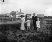 Grupp fem personer. Bostadshus och fabriksbyggnader i  bakgrunden.Emilia Johansson med döttrarna Ingeborg, Brita och Hedvig. Mannen är Karls bror Olof Johansson.Bilden tagen före mars 1915 då Hedvig dog.Platsen Örebro ? Hallsberg?Se även bild 16.