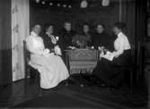 Sex kvinnor med handarbeten ” vy 1917 J” på asken
	Metallutfällning.