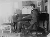 Porträtt av John Bauer vid pianot.