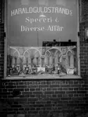Skyltfönster, Harald Gulstrands speceri- & diverse affär ”Guldstrands skyltfönster”
	Metallutfällning, repor, prickhål i emulsionen, fingeravtryck.