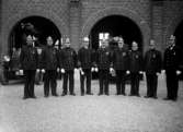 1934 Bandstationens jubileum 9 men i uniformer framför brandstationen
	Metallutfällning, repor, fläckar, missfärgad gult.
