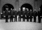 1934 Bandstationens jubileum 9 men i uniformer framför brandstationen
	Metallutfällning, repor, fläckar, missfärgad gult.