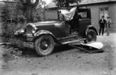 Bagare Lundströms bil. På skylten står M111 76 bilen är krockad 1932
	Metallutfällning, fingeravtryck, missfärgad lätt rosa.