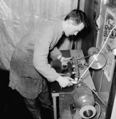 Jacke Pettersson står vid slipmaskinen och slipar skridsko.