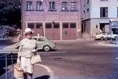 En kvinna vid Gamla Torget i Mölndal, 1970-tal. I bakgrunden ses Kvarnbygatan 41, tidigare brandstation och garage för polisbilar, numera Mölndals målarskola. Till höger ses del av huset Kvarnbygatan 43, tidigare Mölndals stadshus, sedermera musikskola.

För mer information om bilden se under tilläggsinformation.