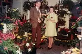 En man och en kvinna fotograferade i blomsteraffären vid Gamla Torget i Mölndal med adress Kvarnbygatan 45, 1970-tal. Kvinnan hette Kerstin och var ägare av affären. Lokalen används numera av Corpus Pizzeria.

För mer information om bilden se under tilläggsinformation.