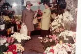 Två kvinnor fotograferade i blomsteraffären vid Gamla Torget i Mölndal med adress Kvarnbygatan 45, 1970-tal. Kvinnan till vänster är tant Kajsa, d.v.s. Kajsa Forsell, som arbetade i garnaffären och kvinnan till höger hette Kerstin och var ägare av blomsteraffären. Lokalen används numera av Corpus Pizzeria.

För mer information om bilden se under tilläggsinformation.